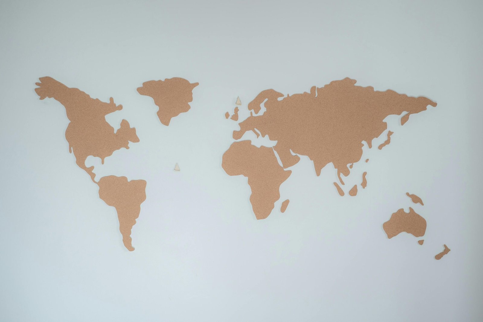 من نحن A minimalist cork board world map displayed on a white wall provides modern decor inspiration.