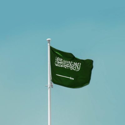 National flag of Saudi Arabia waving on a flagpole against a clear blue sky in Riyadh.