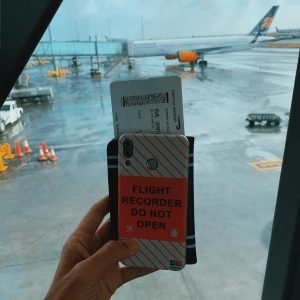 pexels photo 4606721 4606721 Traveler holding a boarding pass with a plane visible through the window at Keflavík Airport.